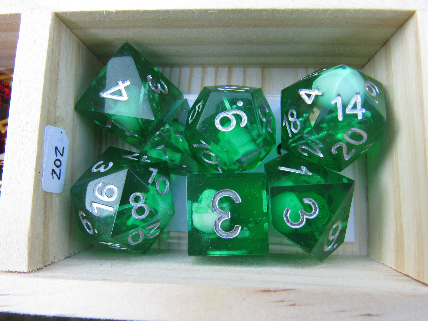Set of green transparent dice with white numbers in a wooden box gelatinous cube