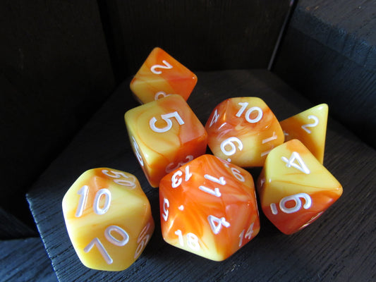 Set of orange and yellow polyhedral dice with white numbers on a dark surface