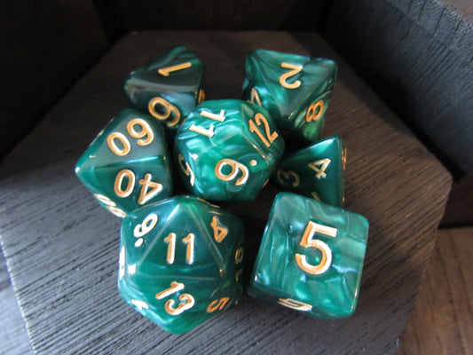 Set of teal polyhedral dice with gold numbers on a wooden surface