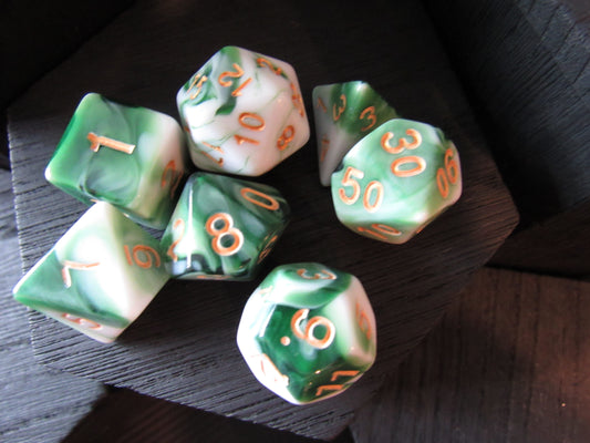 Set of green and white dice with orange numbers on a dark surface