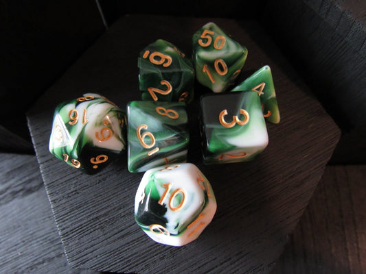 Set of green and black polyhedral dice with gold numbers on a dark surface