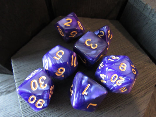 Purple polyhedral dice with gold numbers on a wooden surface