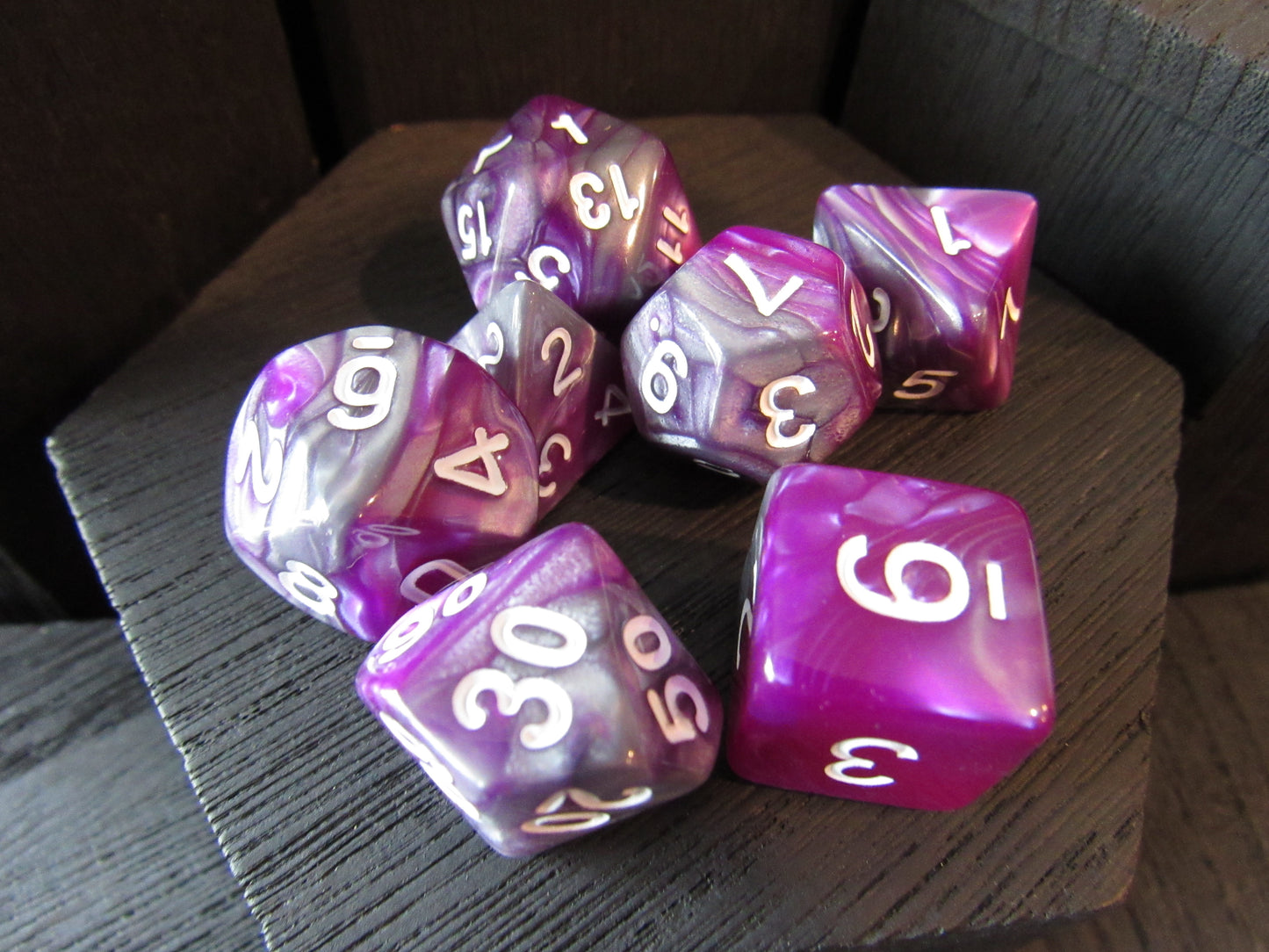 Set of purple and pink polyhedral dice on a wooden surface