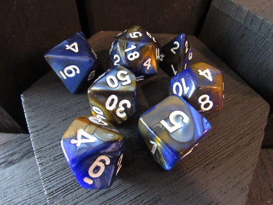 Set of polyhedral dice with blue, brown, and white numbers on a wooden surface.