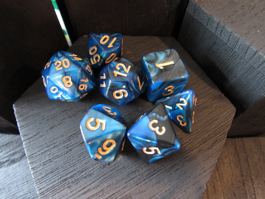 Blue and gray polyhedral dice set with gold numbers on a wooden surface