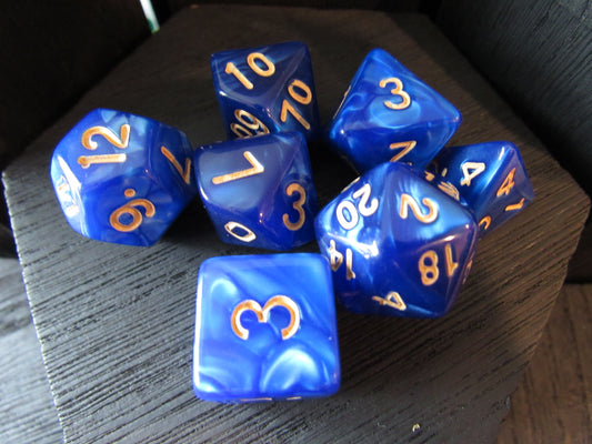 Set of blue polyhedral dice with gold numbers on a wooden surface