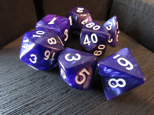 Set of purple polyhedral dice with white numbers on a wooden surface