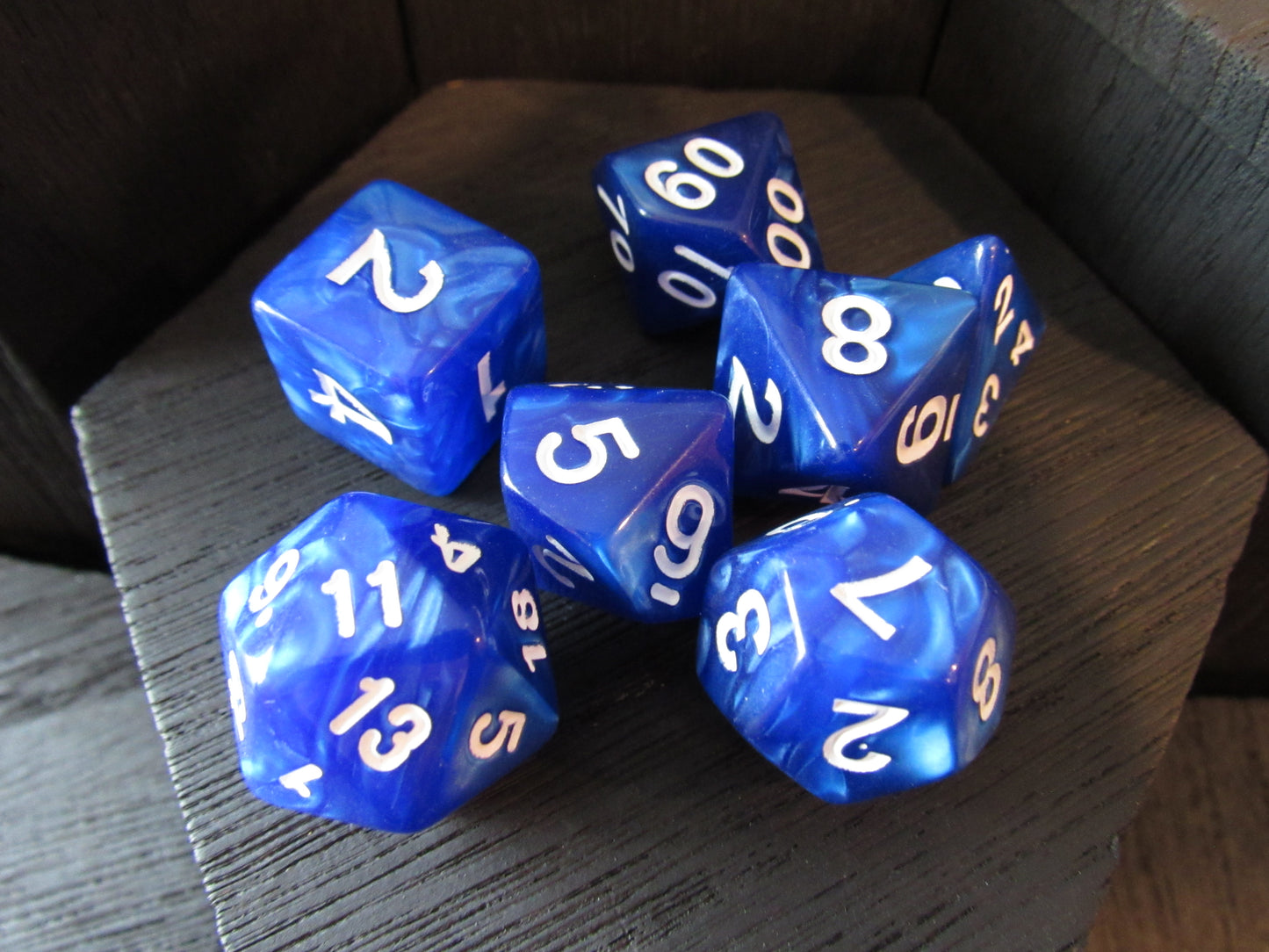 Blue polyhedral dice with white numbers on a wooden surface
