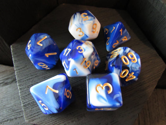 Set of blue and white dice with orange numbers on a wooden surface