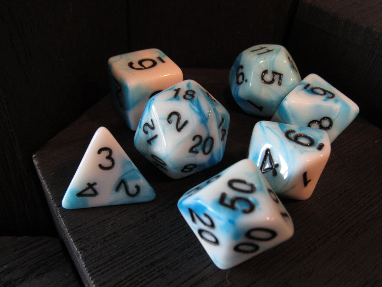 Set of polyhedral dice with blue and white color scheme on a dark surface