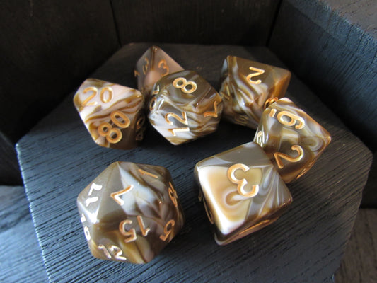 Set of seven polyhedral dice with gold and brown marbled pattern on a dark surface