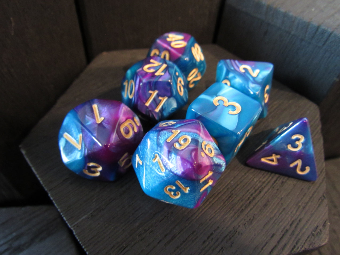 Set of blue and purple polyhedral dice on a dark surface