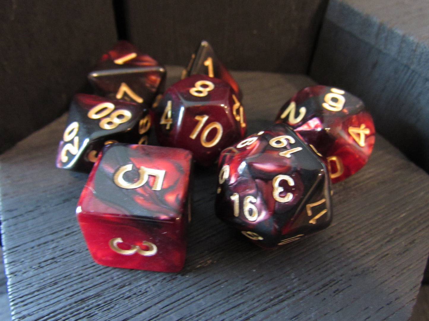 Set of red and black dice with gold numbers on a wooden surface
