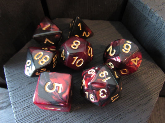 Set of polyhedral dice with red and black marbled pattern on a wooden surface