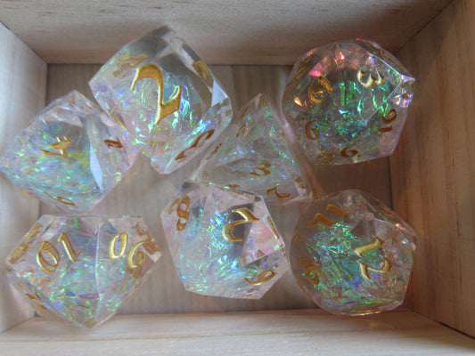 Set of iridescent polyhedral dice with gold numbers on a wooden surface gem gemstone cut faceted resin dice set