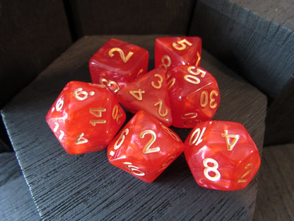 Red polyhedral dice with gold numbers on a dark surface