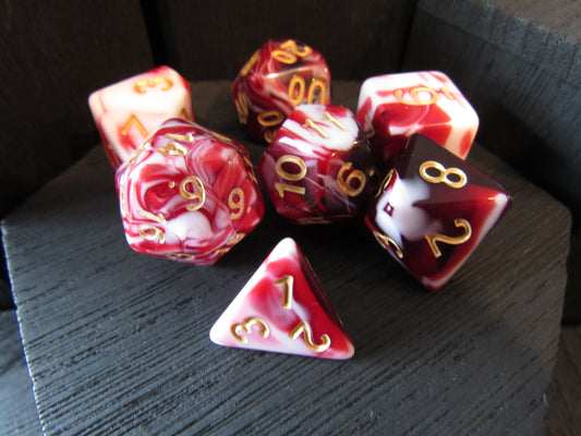 Set of red and white marbled dice with gold numbers on a dark surface