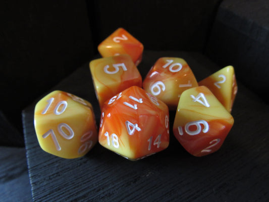 Set of orange and yellow polyhedral dice with white numbers on a dark surface