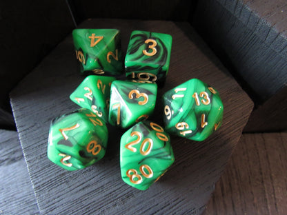 Set of green polyhedral dice with gold numbers on a dark wooden surface