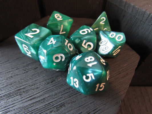 Set of green polyhedral dice with white and yellow numbers on a wooden surface