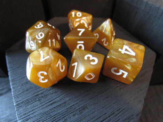 Set of amber-colored polyhedral dice with white numbers on a textured surface.