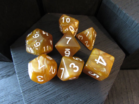 Set of amber-colored polyhedral dice with white numbers on a dark surface