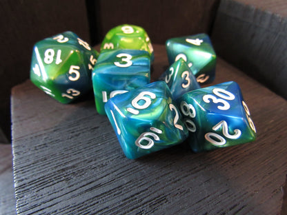 Set of green and blue dice with white numbers on a wooden surface