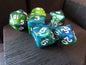 Set of green and blue dice with white numbers on a wooden surface