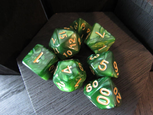 Green polyhedral dice set with gold numbers on a wooden surface