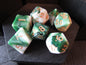 Set of green and white polyhedral dice with orange numbers on a wooden surface