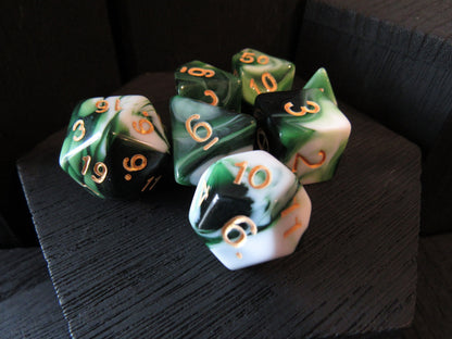 Set of green and white polyhedral dice with gold numbers on a dark surface