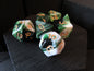 Set of green and white polyhedral dice with gold numbers on a dark surface