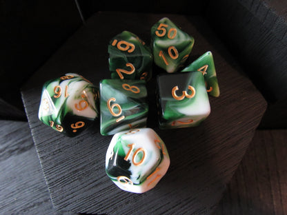 Set of green and black polyhedral dice with gold numbers on a dark surface