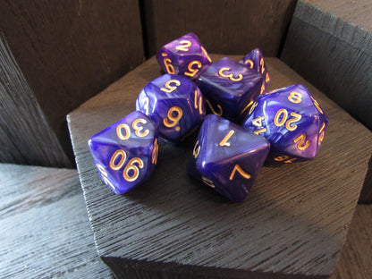 Purple polyhedral dice with gold numbers on a wooden surface