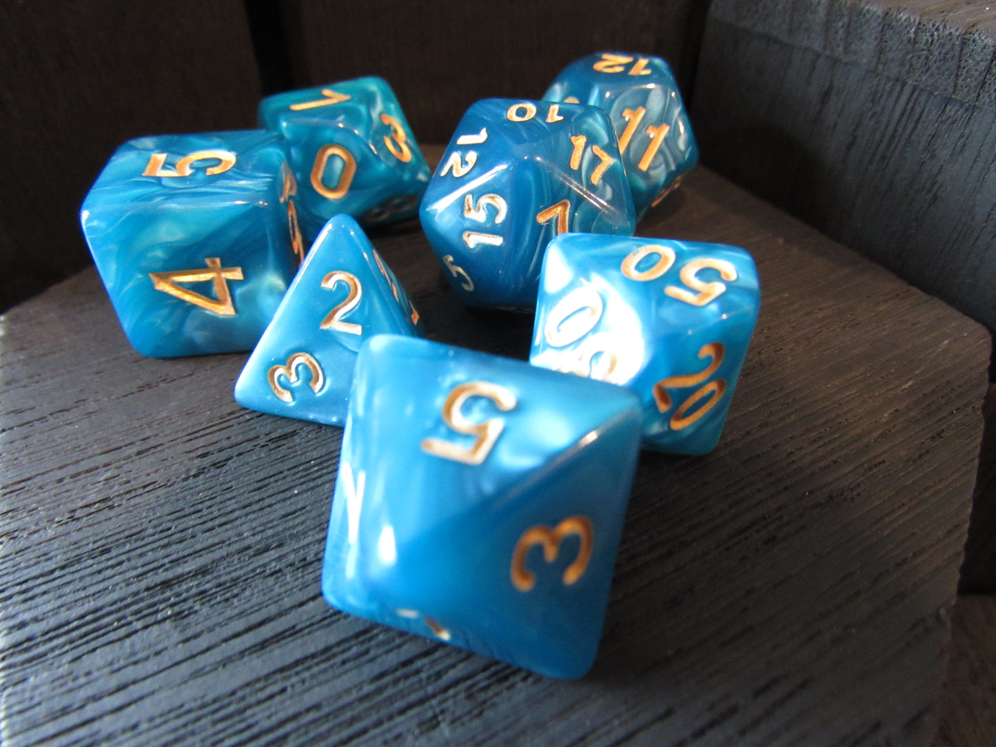 Blue polyhedral dice with gold numbers on a wooden surface