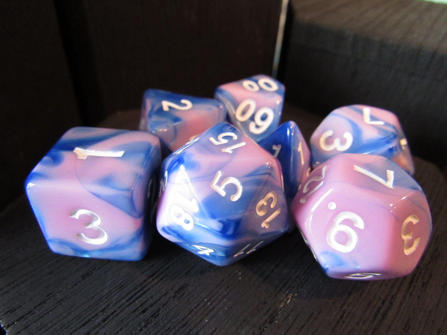 Set of blue and pink dice with white numbers on a dark surface