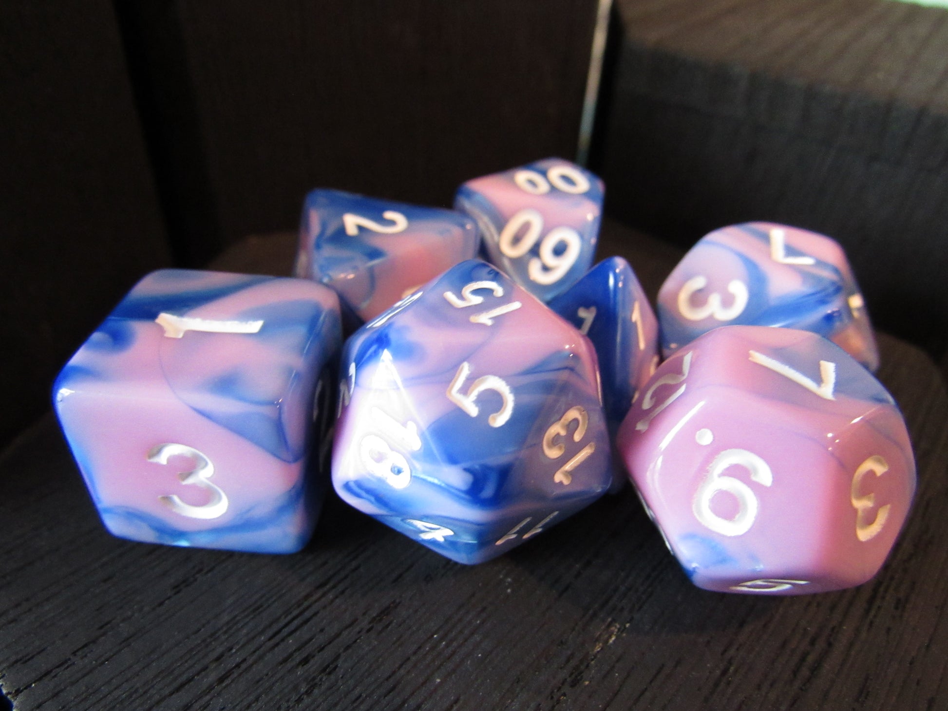 Set of blue and pink dice with white numbers on a dark surface