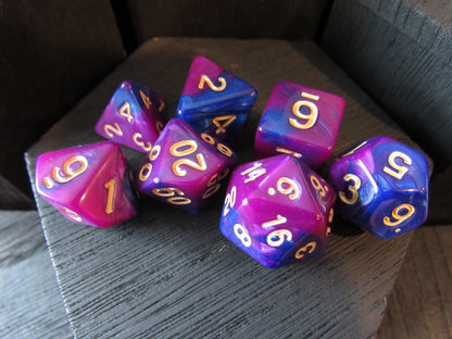 Set of purple and blue polyhedral dice with gold numbers on a wooden surface.