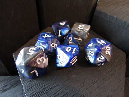 Set of blue and silver polyhedral dice on a wooden surface