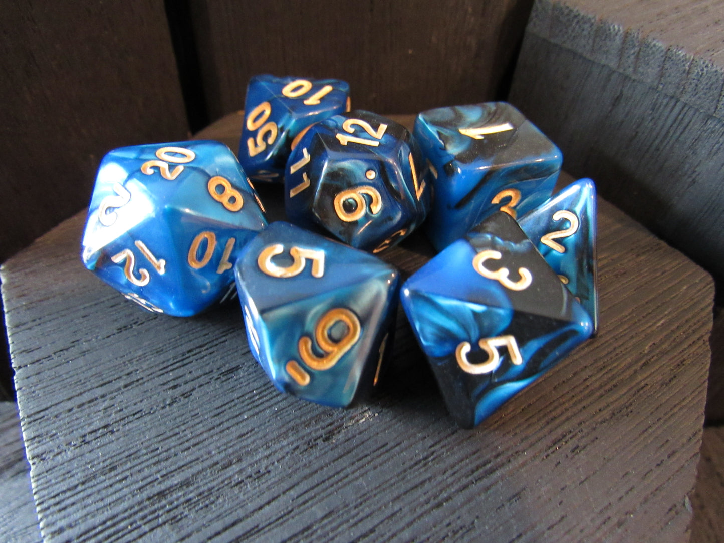 Set of blue polyhedral dice with gold numbers on a wooden surface