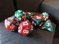 Set of polyhedral dice with red, green, and brown colors on a wooden surface.