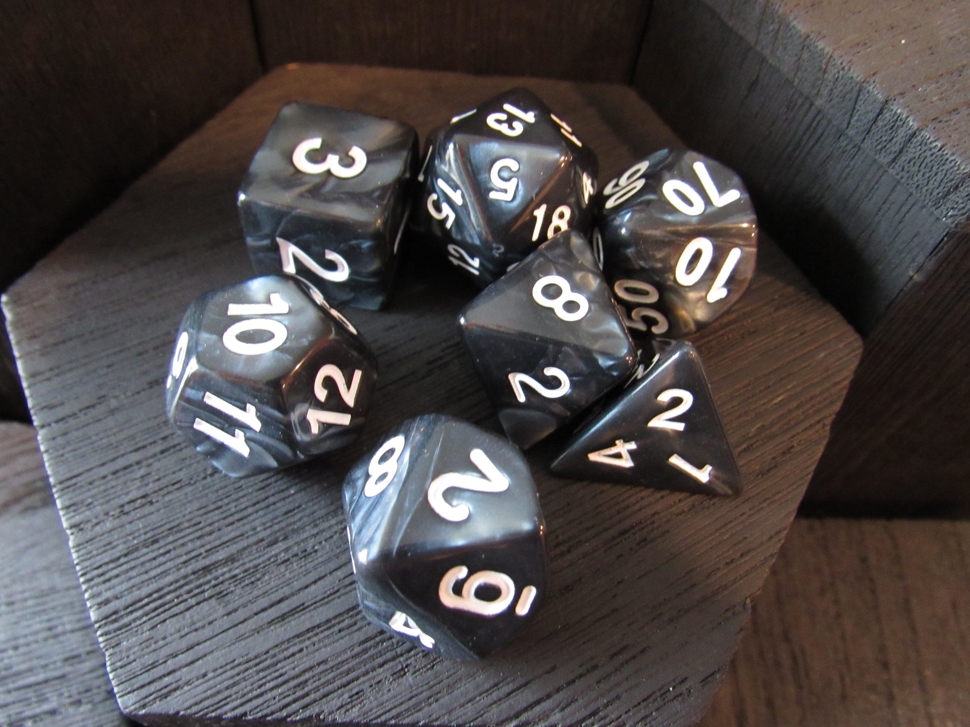 Set of polyhedral dice with white numbers on a wooden surface