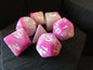 Pink and white polyhedral dice set on a dark surface