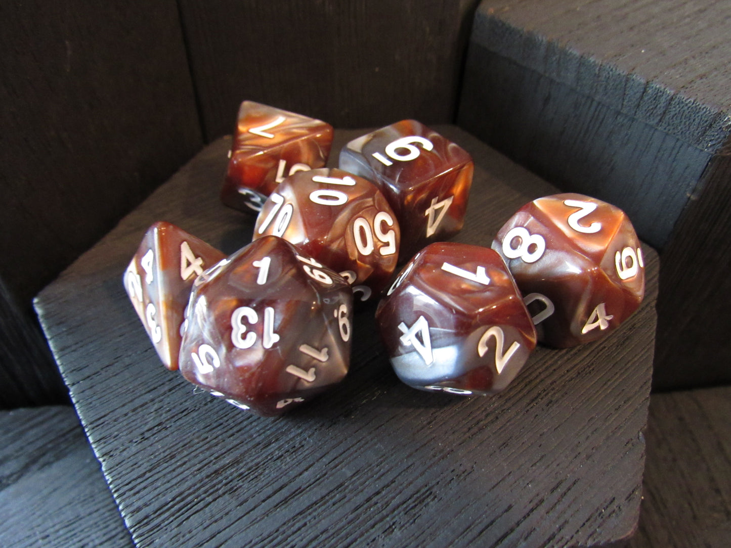 Set of polyhedral dice with brown and white colors on a dark surface