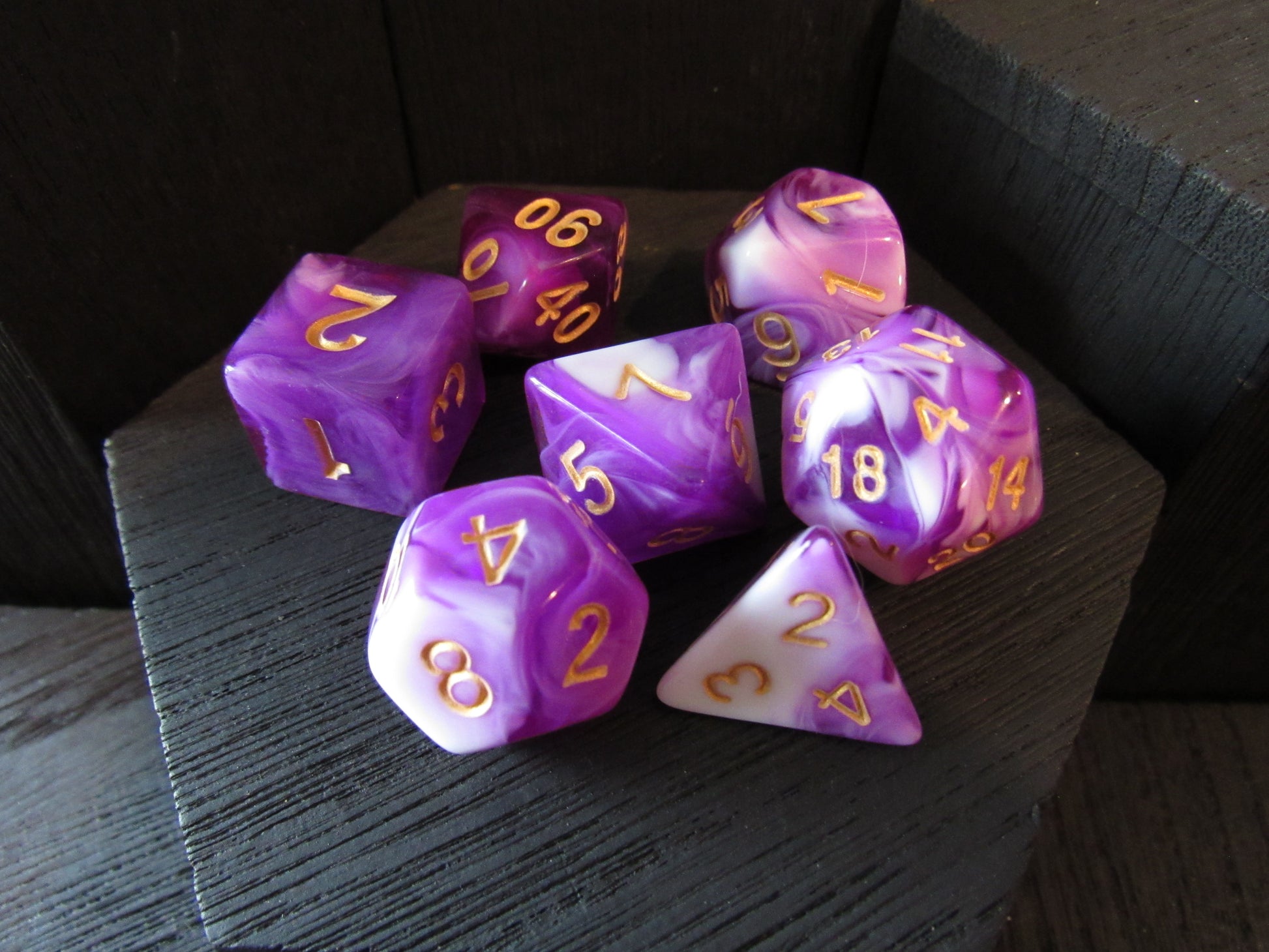 Purple and white polyhedral dice set on a dark surface