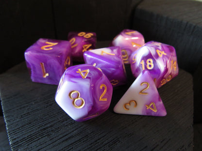 Set of purple and white polyhedral dice with gold numbers on a dark surface