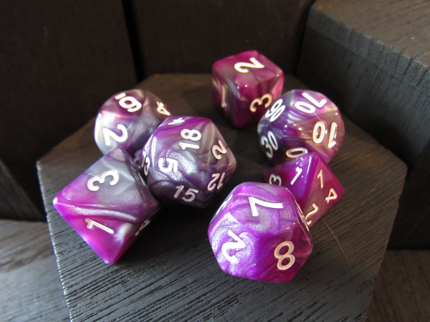 Purple and pink polyhedral dice set on a wooden surface