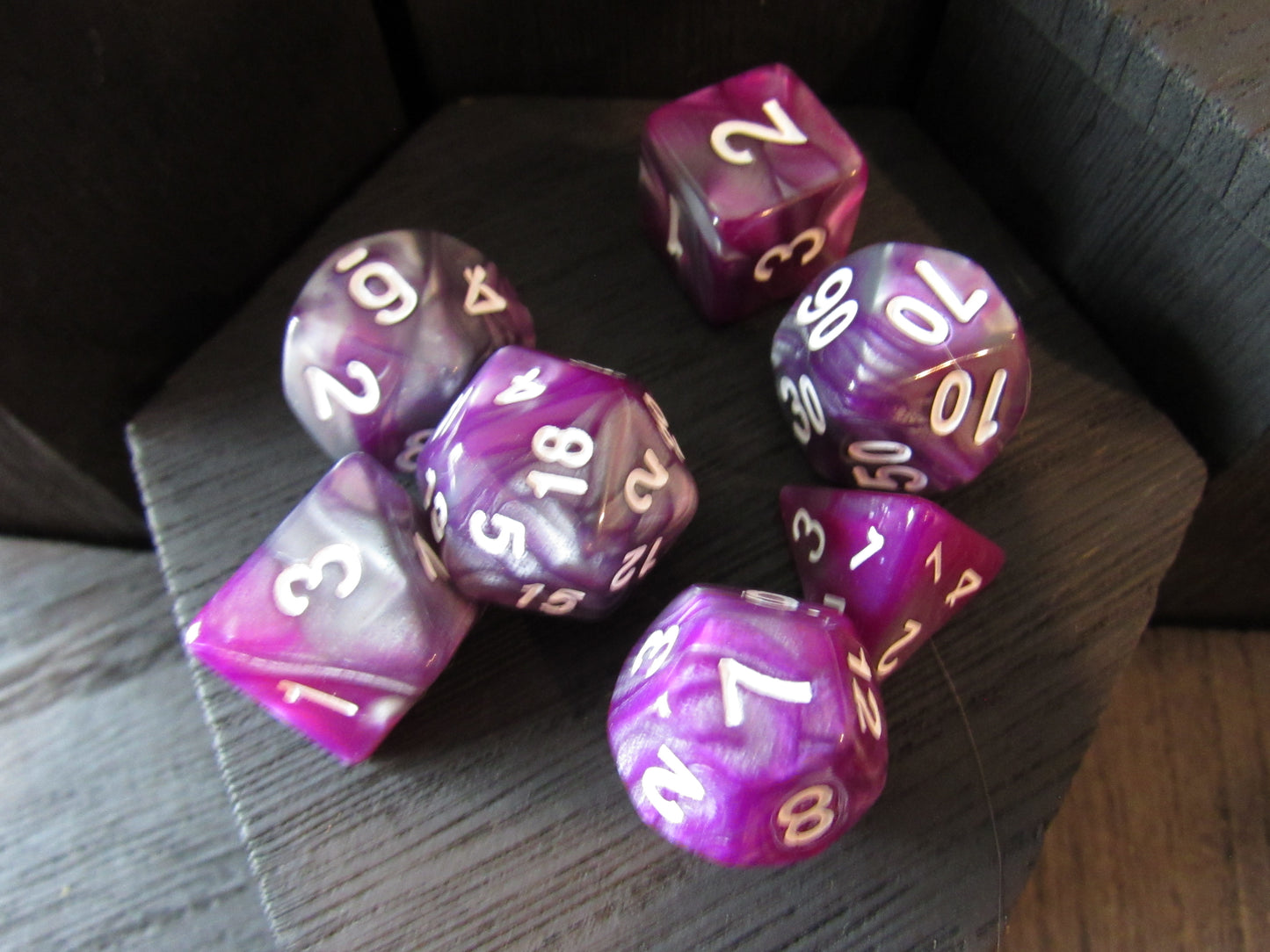 Purple and white polyhedral dice set on a wooden surface