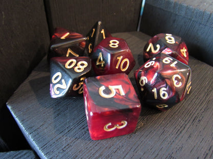 Set of polyhedral dice with red and black marbled pattern on a dark surface