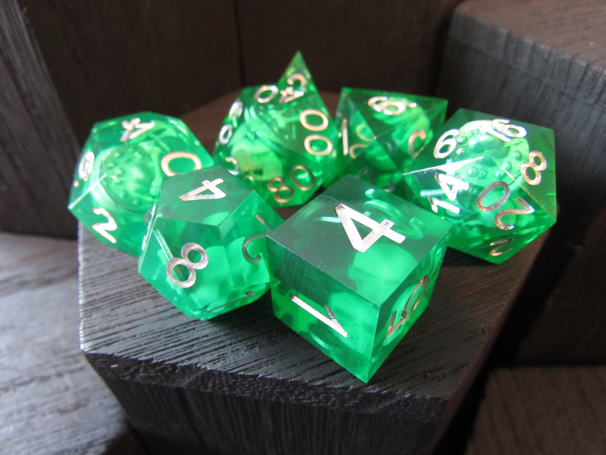 Set of green dice with gold numbers on a wooden surface gelatinous cube
